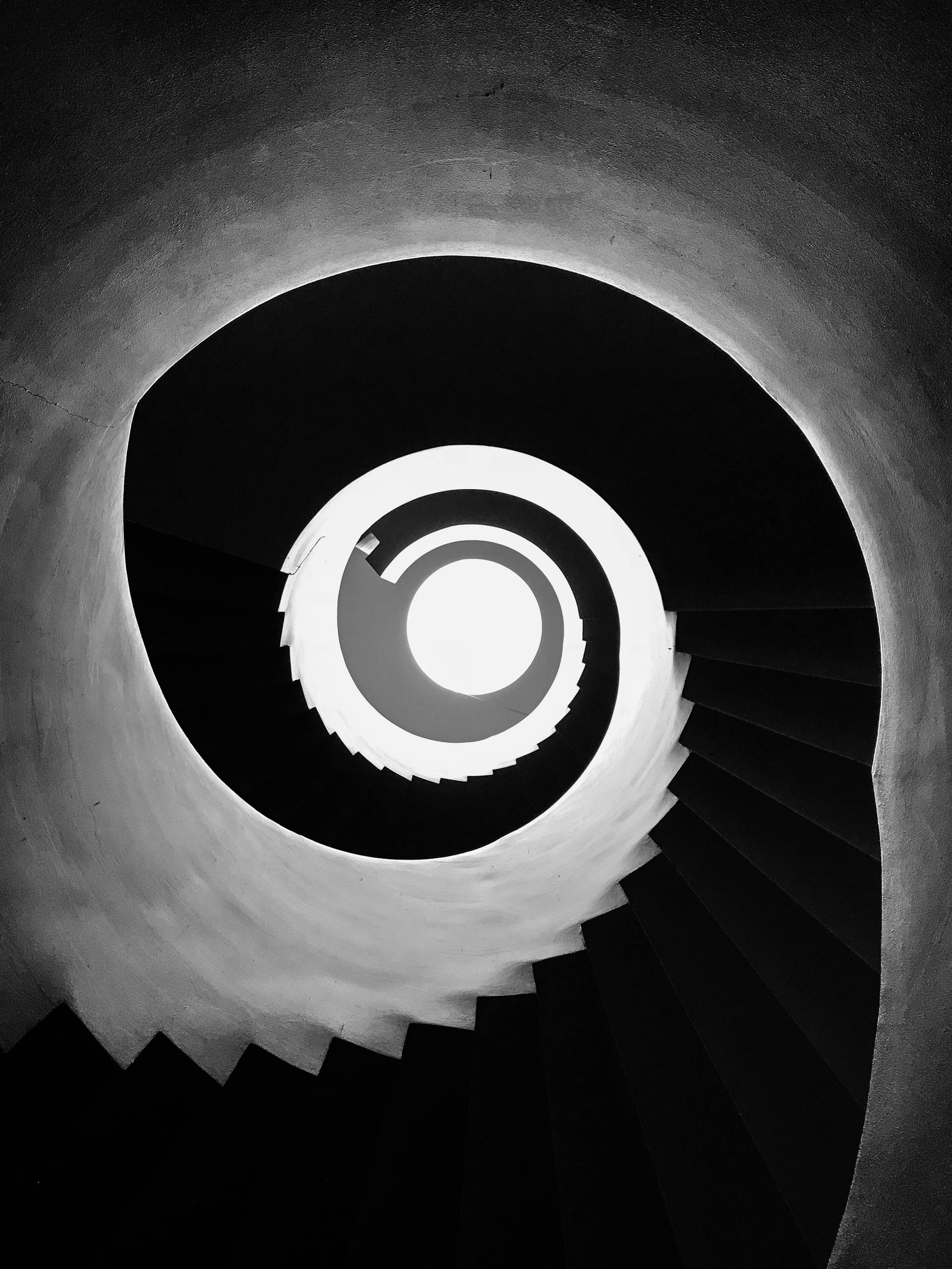 A black and white spiral staircase viewed from below, creating a dramatic abstract design.